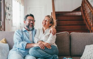 Happy couple laughing while sitting on sofa in the living room